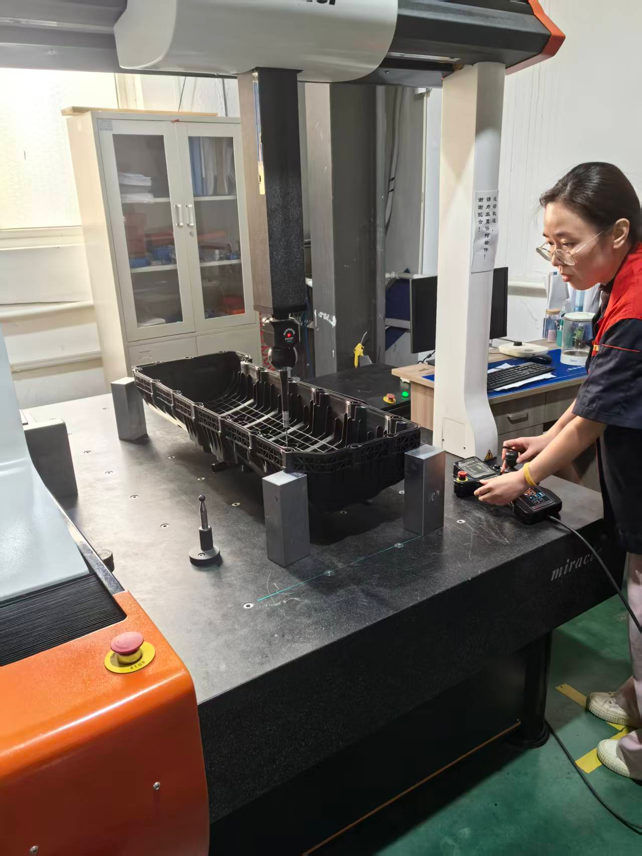 ACXTA operator running a coordinate-measuring machine on a black plastic part